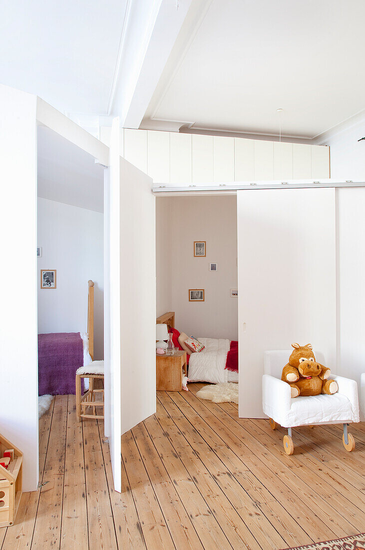 Brightly decorated children's room with partitions, white armchair and soft toy