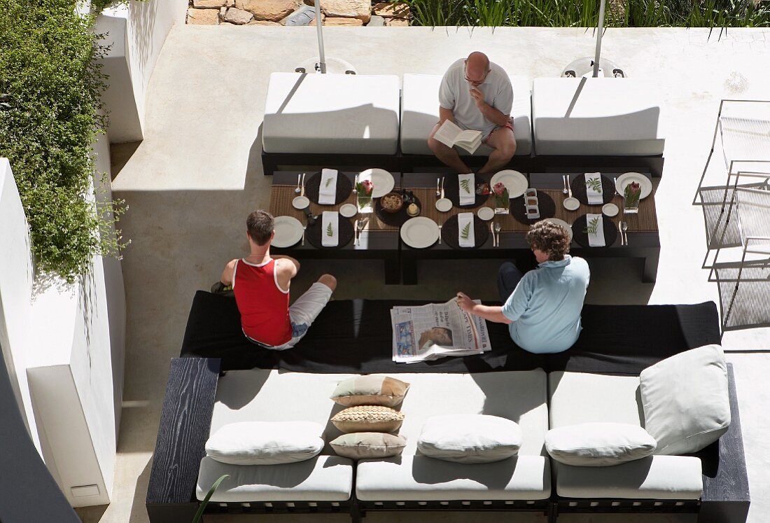 Familie am gedeckten Tisch auf sonnenbeschienener Terrasse