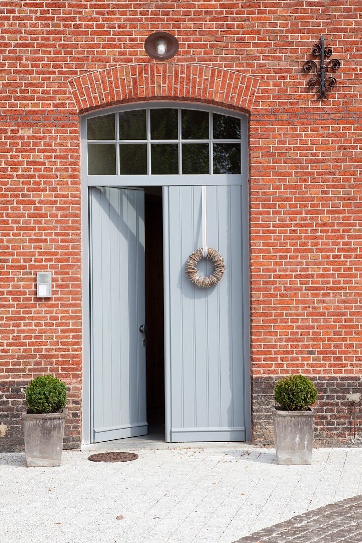 Simple, grey, double front doors in red brick facade of house