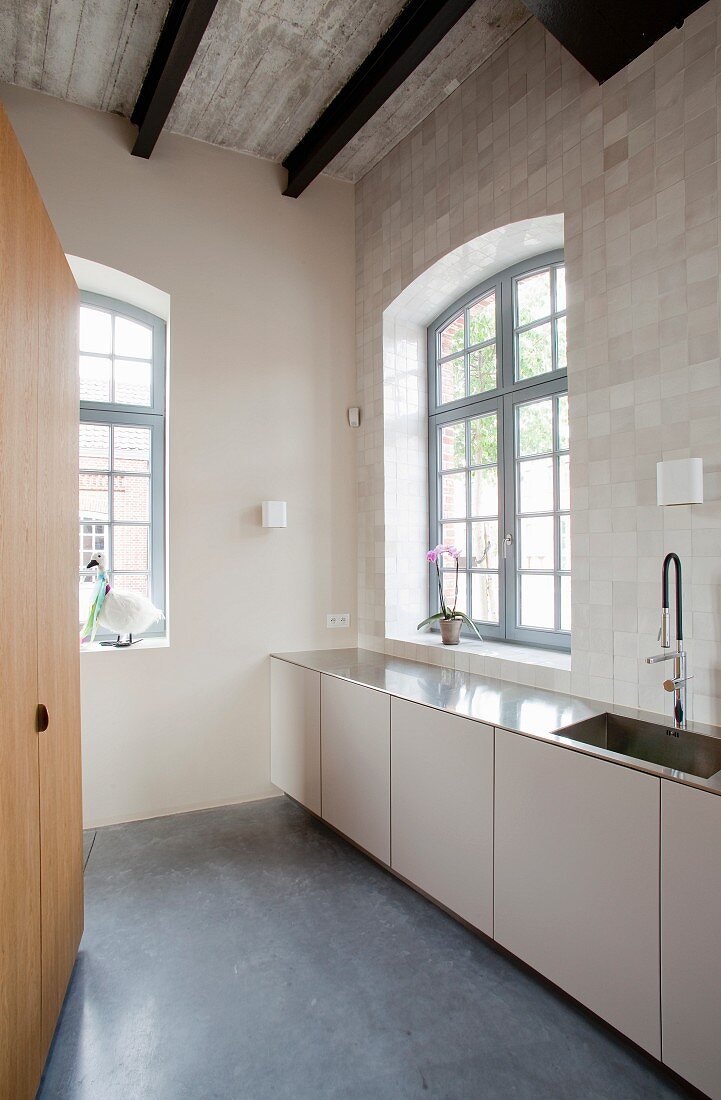 Moderne, minimalistische Küche mit Sprossenfenstern im alten Industriestil und gebogenem Betondach auf schwarzen Stahlträgern