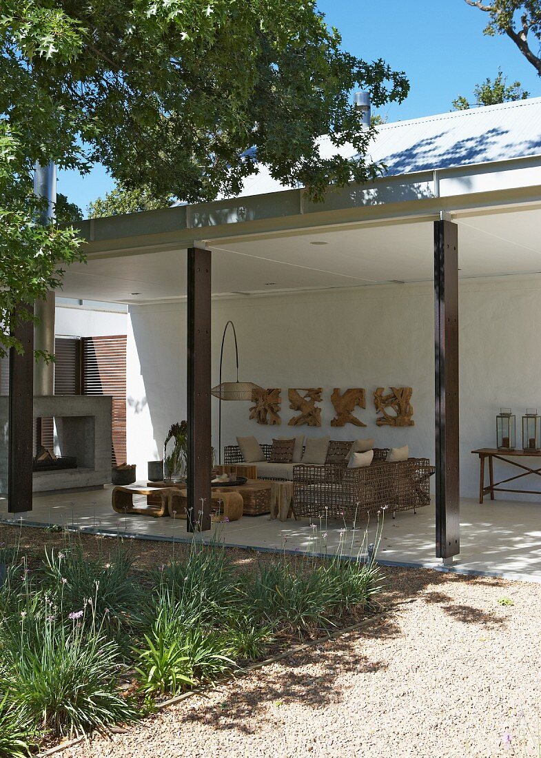 Zeitgenössisches Wohnhaus mit gemütlichen Loungemöbeln aus Naturmaterialien auf einer überdachten Terrasse