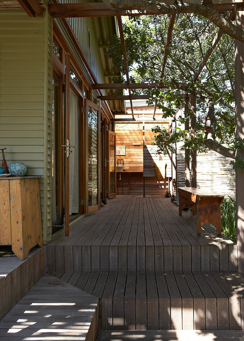 Holzterrasse mit Pergola, Sitzbank im Schatten von Bäumen