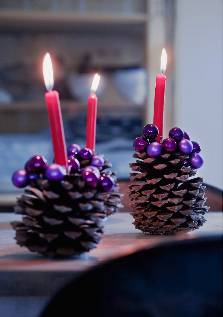 Grosse Zapfen mit lila Perlen verziert, als Kerzenständer