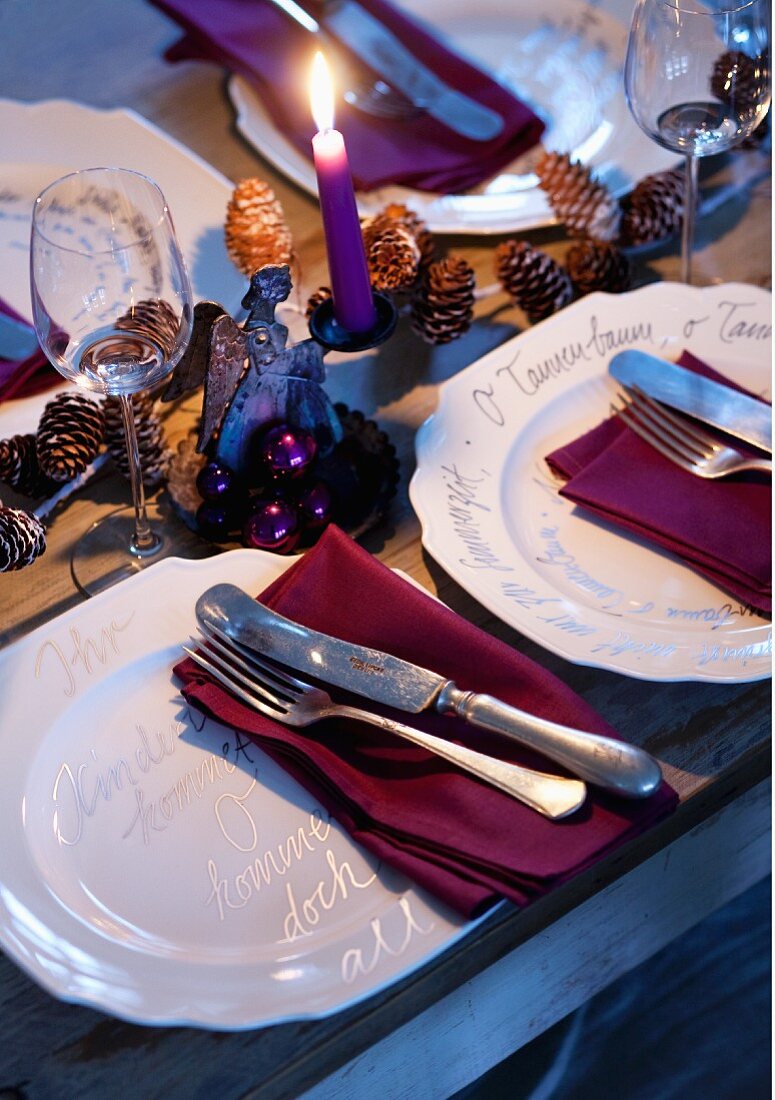 White china plates decorated with carol lyrics on festively set table