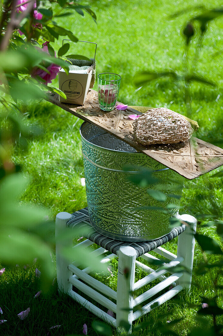 DIY-Konstruktion aus Holzbrett, Pflanzkübel und Hocker im Garten