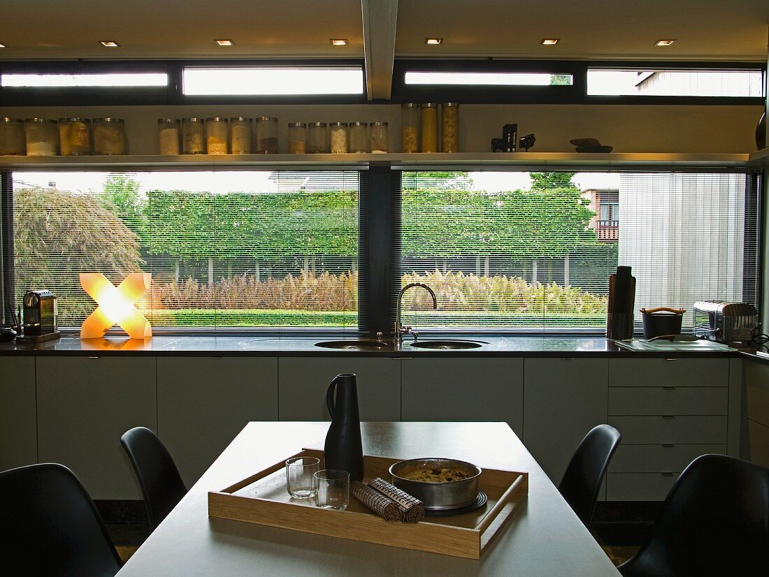Essplatz vor moderner Küchenzeile an Fensterfront mit Gartenblick