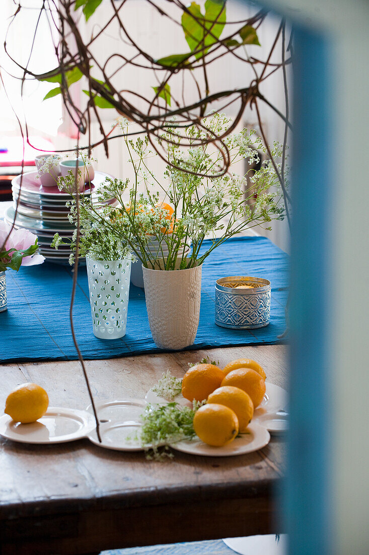 Tisch mit blauem Tischläufer, Zitronen und Blumenvasen