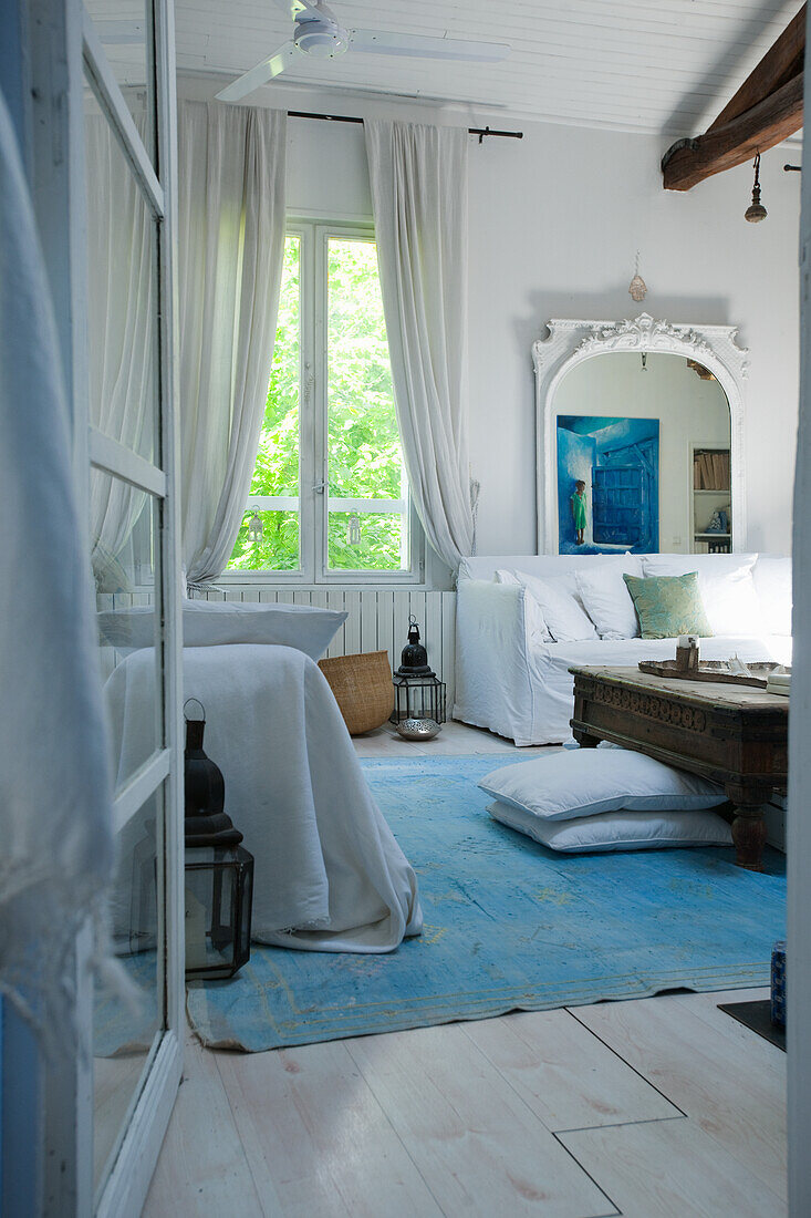 Living room with white furniture, blue carpet and large mirror