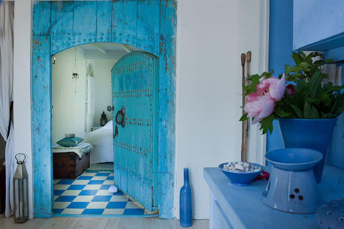 View into bedroom, blue wooden door in oriental style, blue and white chequered floor