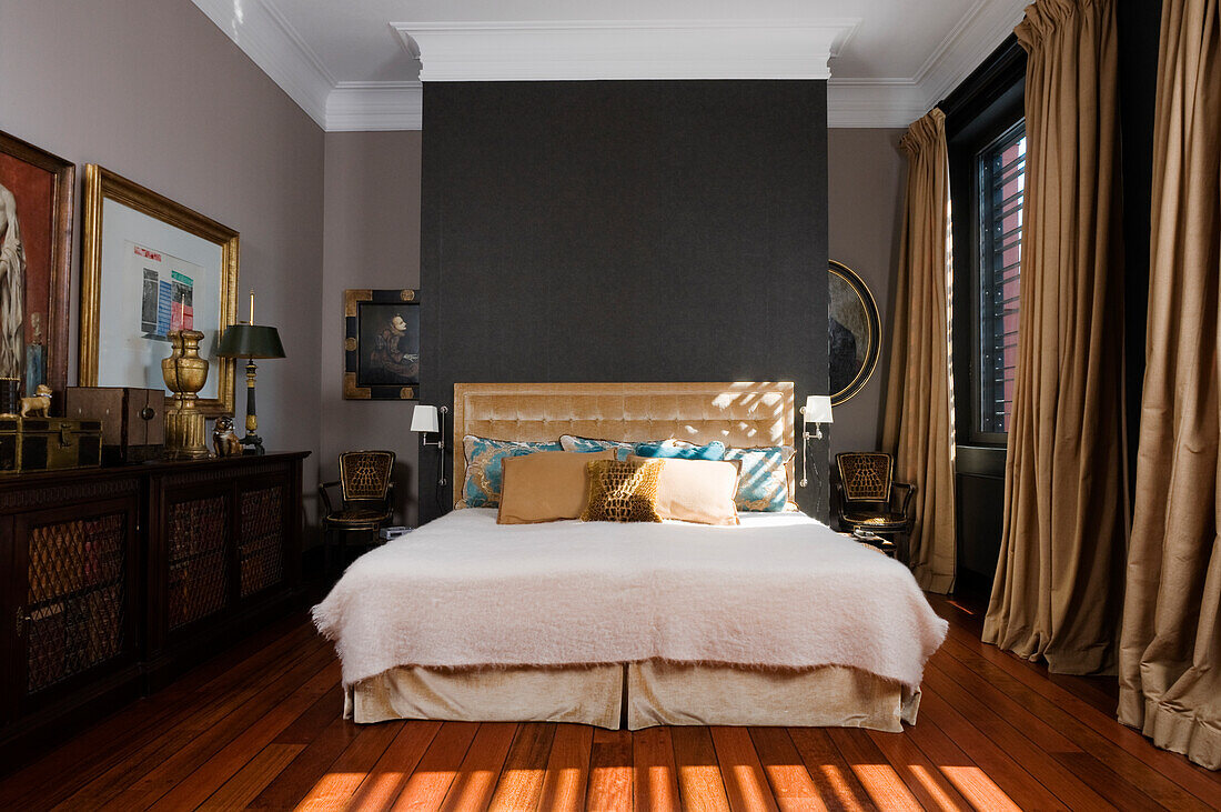 Bedroom with velvet headboard, wooden floor and heavy curtains