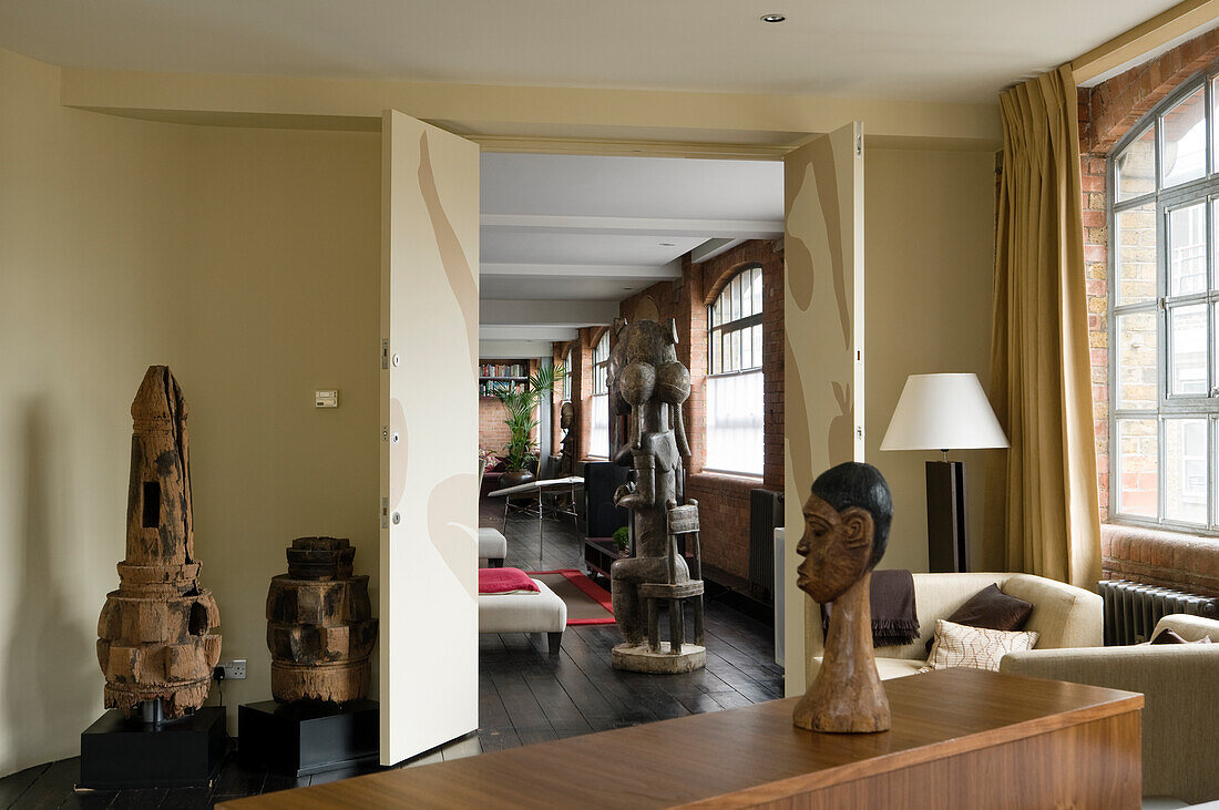 Spacious living area with ethnic wooden sculptures and mullioned windows