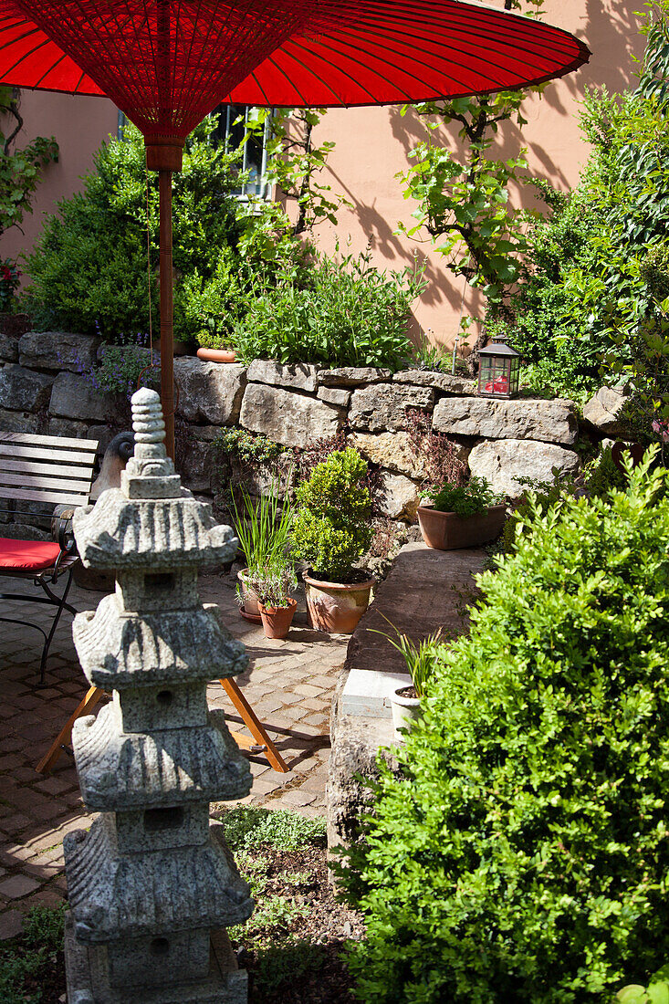 Asian-inspired garden corner with red parasol and sculpture