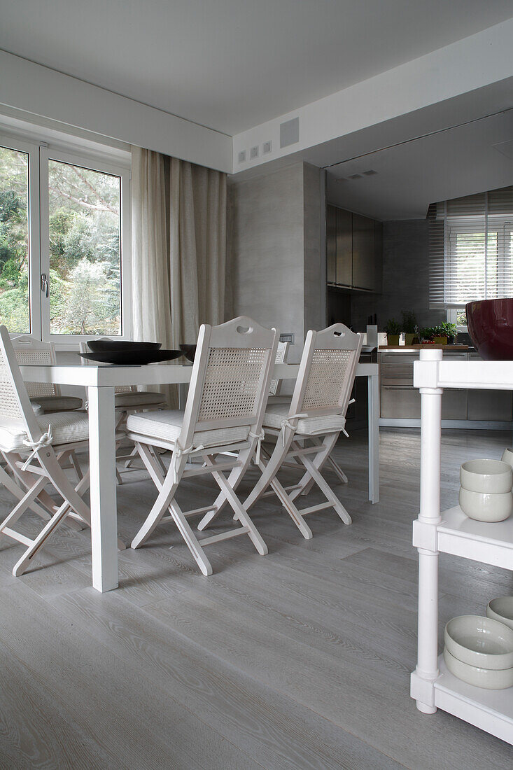 White folding chairs at the dining table in the open-plan living room