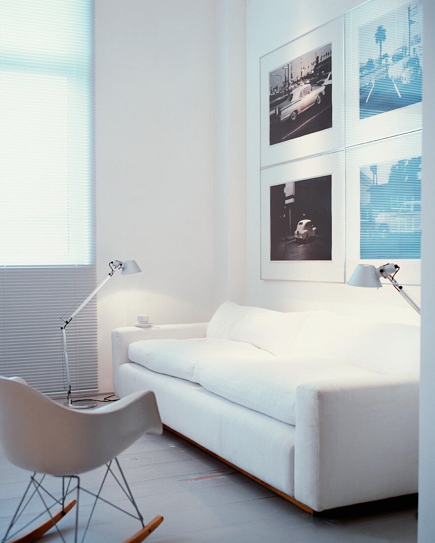 Weisses Sofa vor Photograpien hinter Glas und Bauhausstuhl