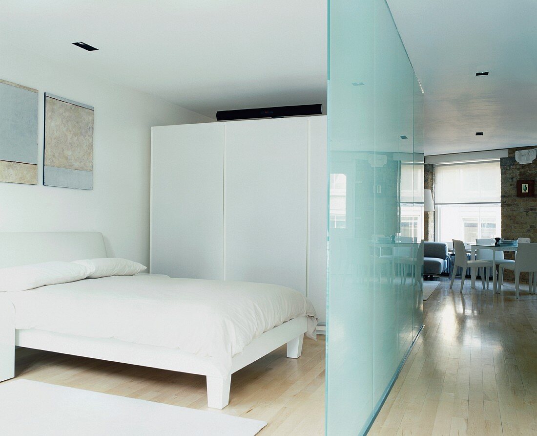 Glass partition separating sleeping area in open-plan living space