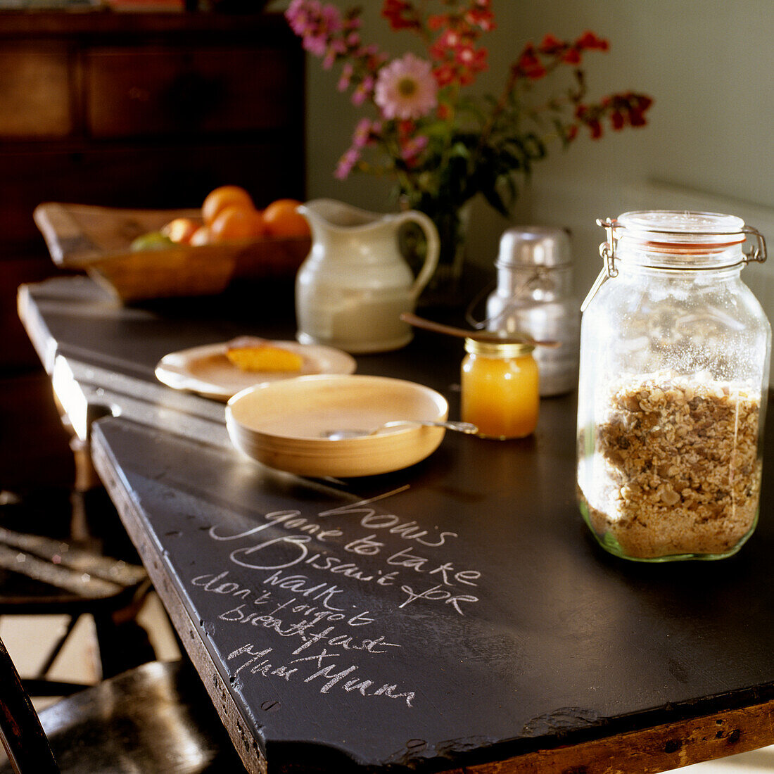 Breakfast table with muesli in a glass jar, bowl and jug