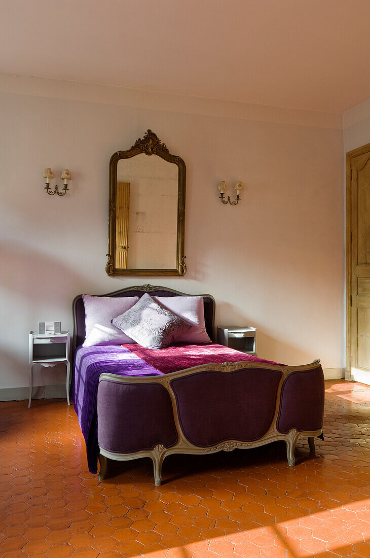 Baroque bed with purple bedspread in a historic bedroom