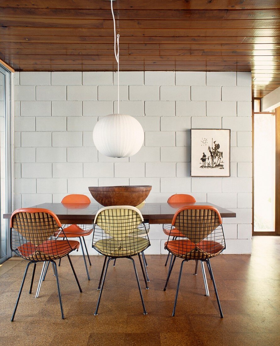 Dining area with wire mesh chairs in dining room with sand-lime brick wall