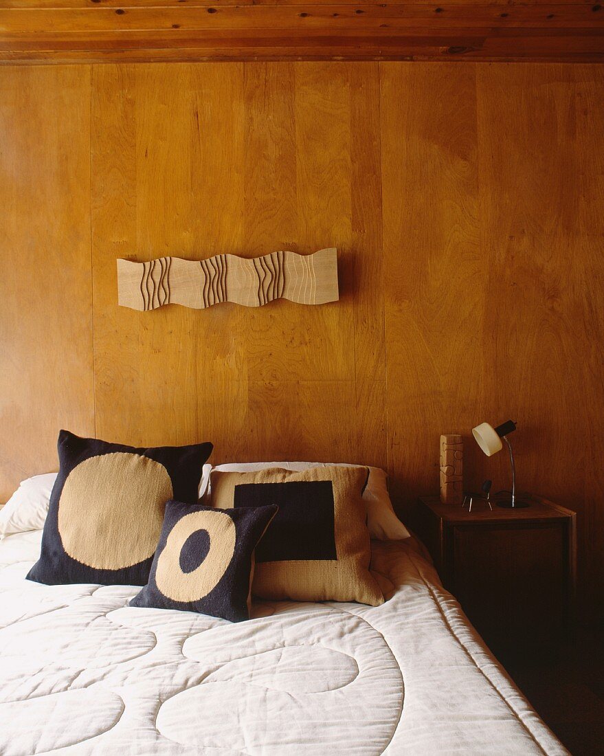 Double bed in front of wood-panelled wall in 50s-style bedroom