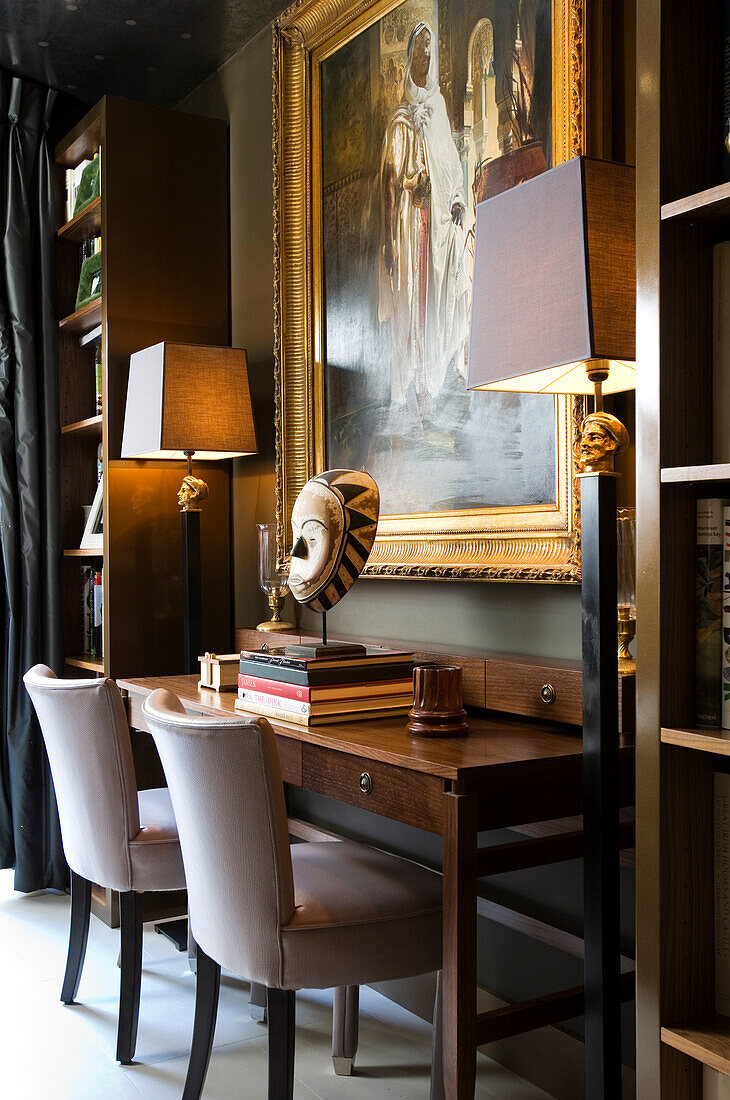 Desk with mask and books, large painting with golden frame