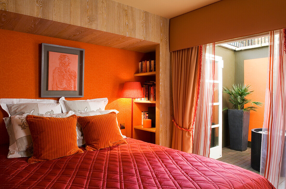 Bedroom with bed in shades of red and access to terrace