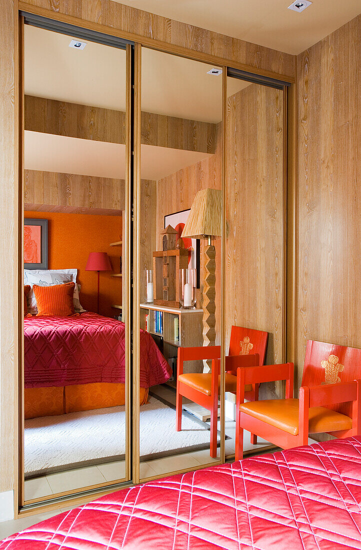 Mirrored wardrobe in bedroom with red accents and wooden elements