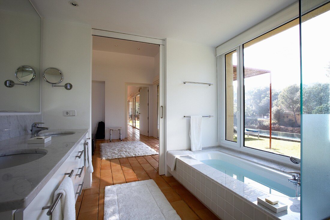 Helles Badezimmer mit raumhohem Fenster, Schiebetür und Terrakottafliesen