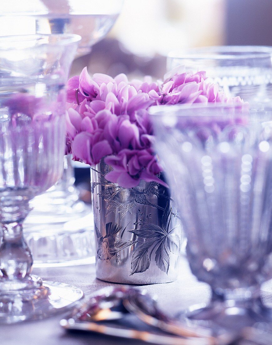 Violette Blumendeko auf gedecktem Tisch