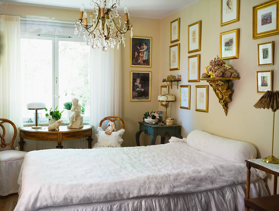 Einfaches Einzelbett im Schlafzimmer mit Bilderwand und antiken Holzmöbeln