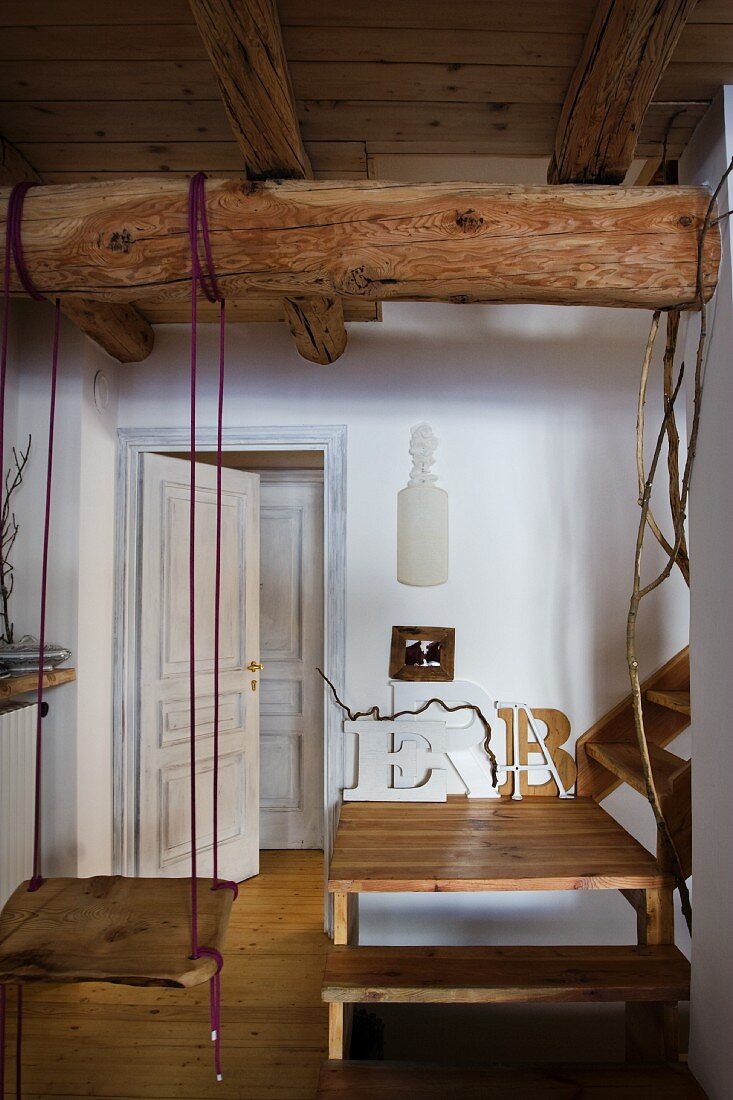 Schaukel an Holzbalken unter Decke befestigt und Holztreppe mit Podest