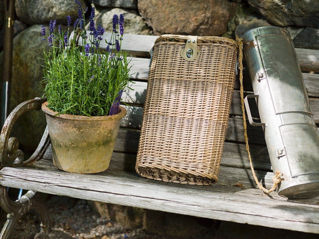 Lavender, wicker bag and metal container on old wooden bench