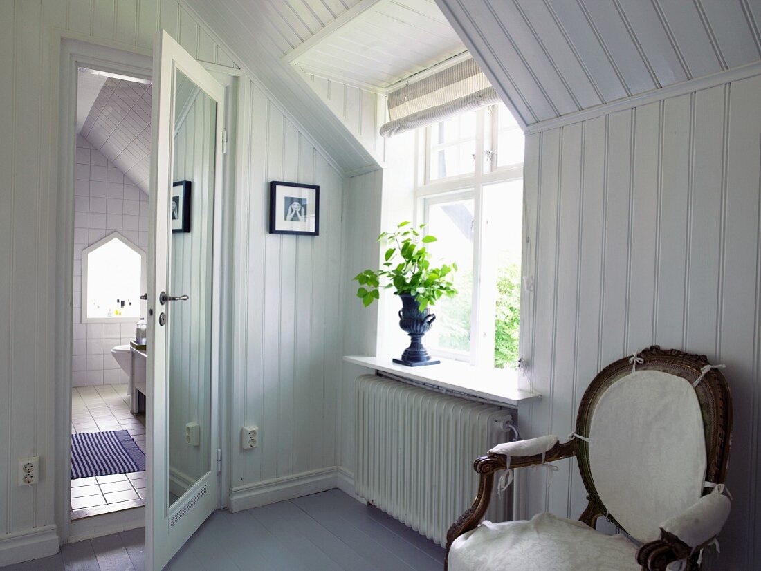 Holzverkleideter Raum mit Stuhl und Blick ins Badezimmer