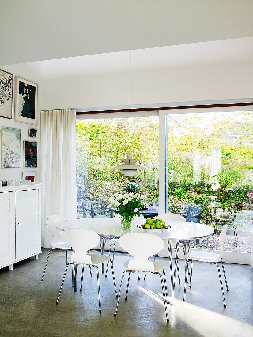 Dining area with white chairs and a view of the garden