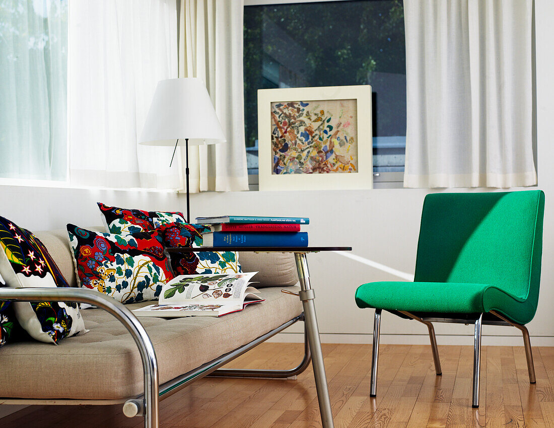 Sofa mit bunten Kissen und grünem Stuhl im modernen Wohnzimmer