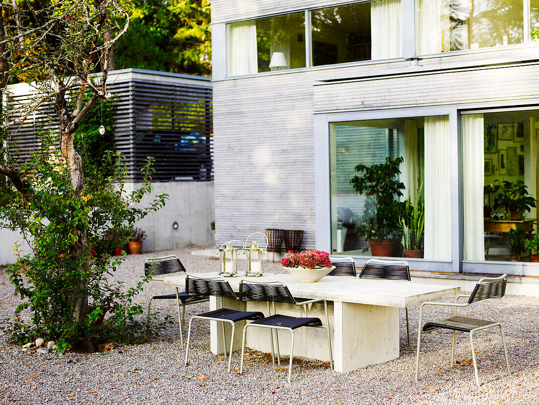 Terrasse mit Esstisch aus Beton und modernen Stühlen im Außenbereich