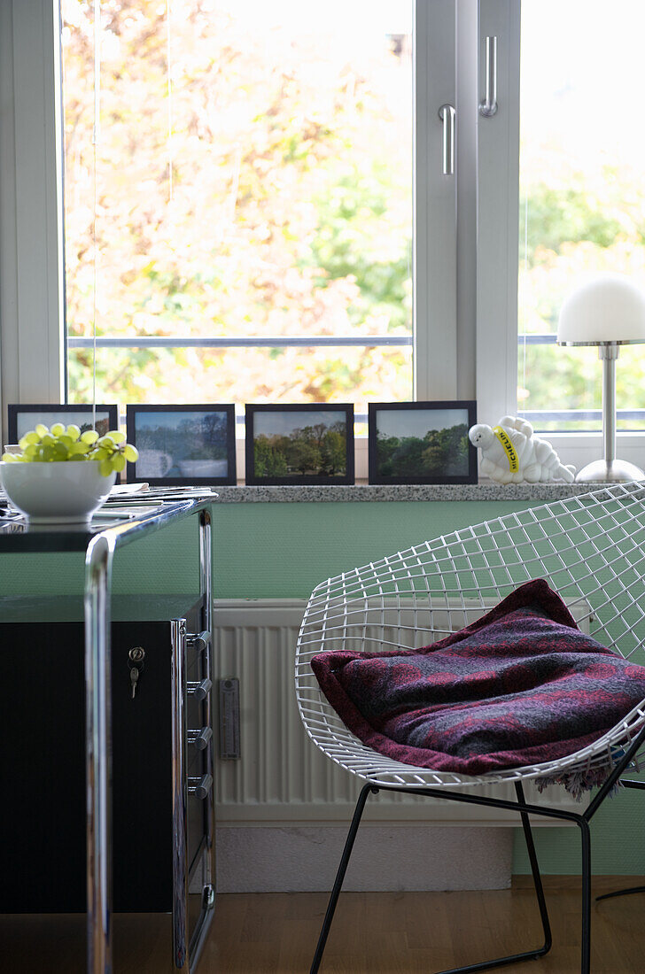 Metal serving trolley and modern wire chair by the window in a reading corner