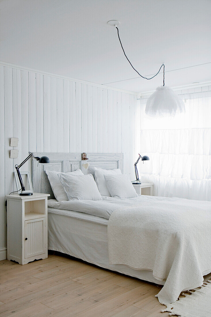 Bedroom in white with double bed, bedside tables and pendant light