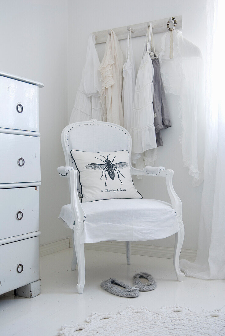White vintage chair with cushion with insect illustration in front of wardrobe