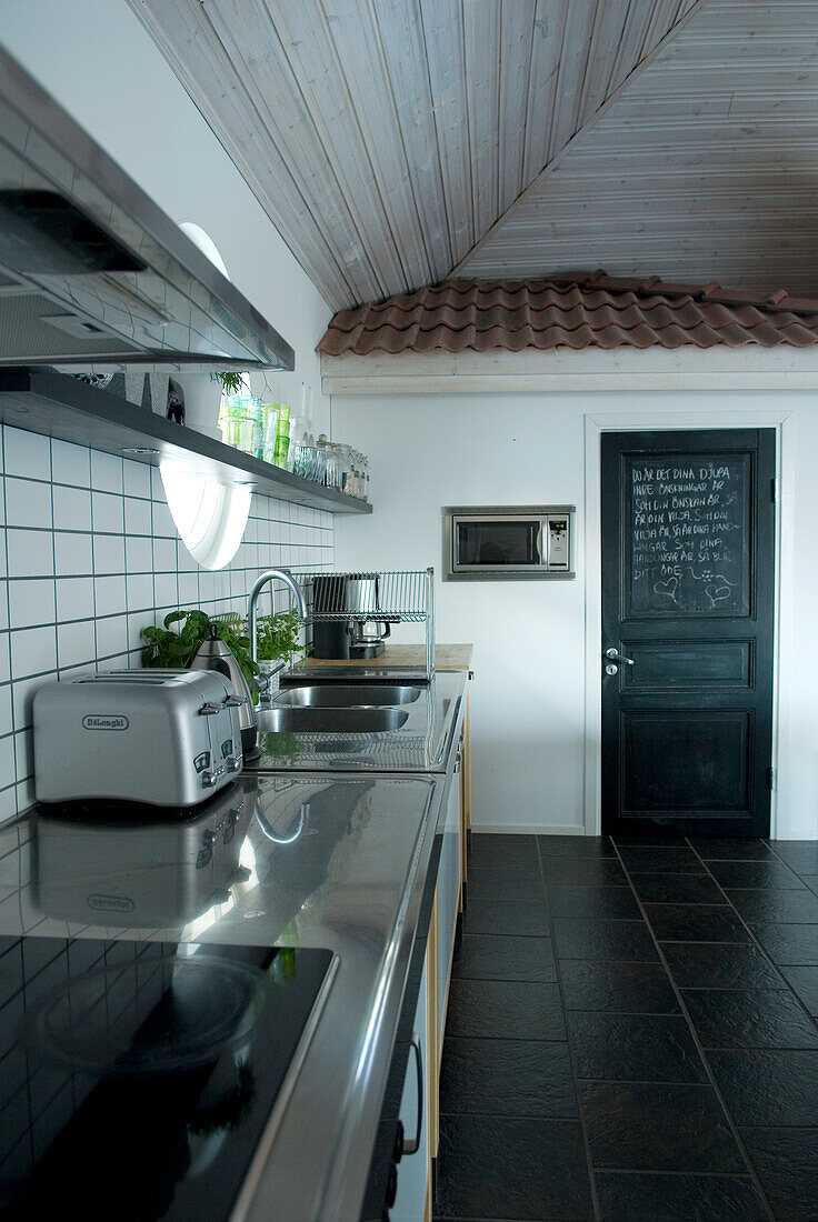 Moderne Küche mit schwarzen Bodenfliesen und schwarzer Tür, die als Tafel fungiert