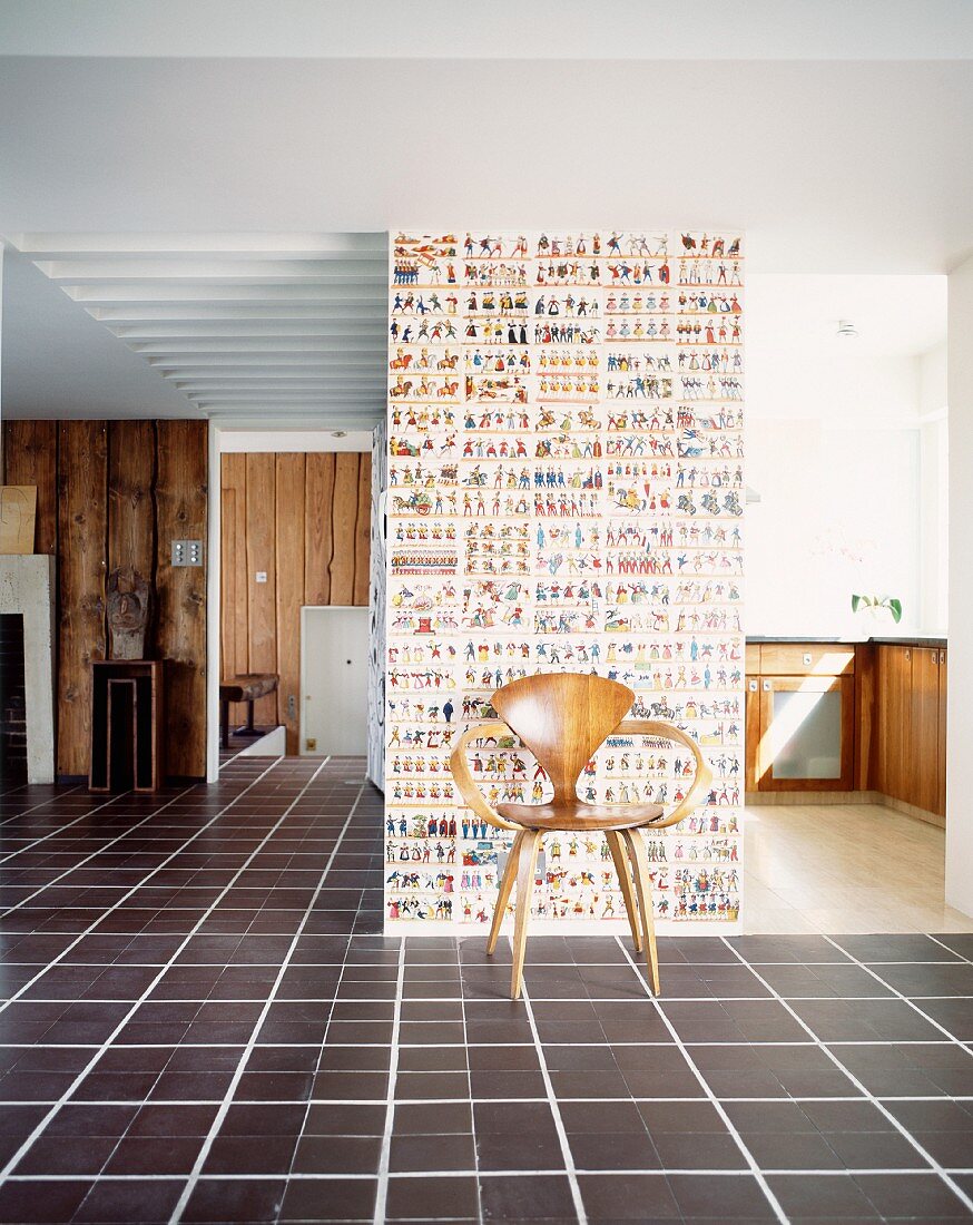 Klassiker Holzstuhl vor Wand mit gemusterter Tapete im offenen Wohnraum