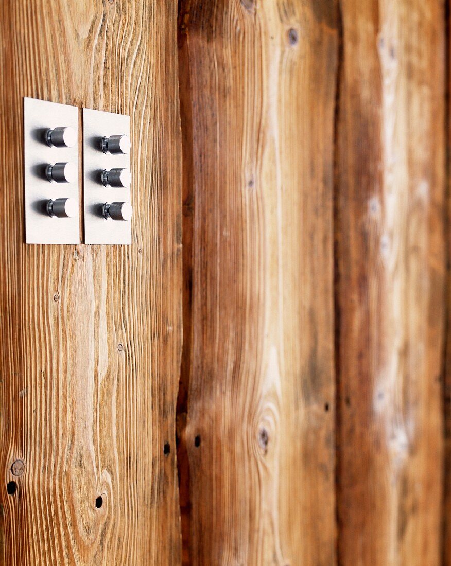 Lichtschalter-Drehknöpfe aus Edelstahl an Holzwand