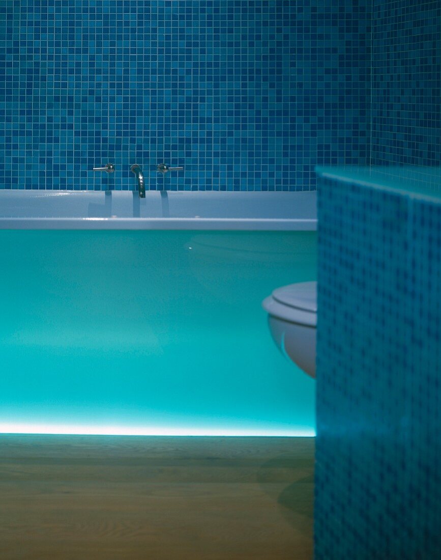 Badewanne mit indirekter Beleuchtung in einem Badezimmer mit blauen Mosaikfliesen