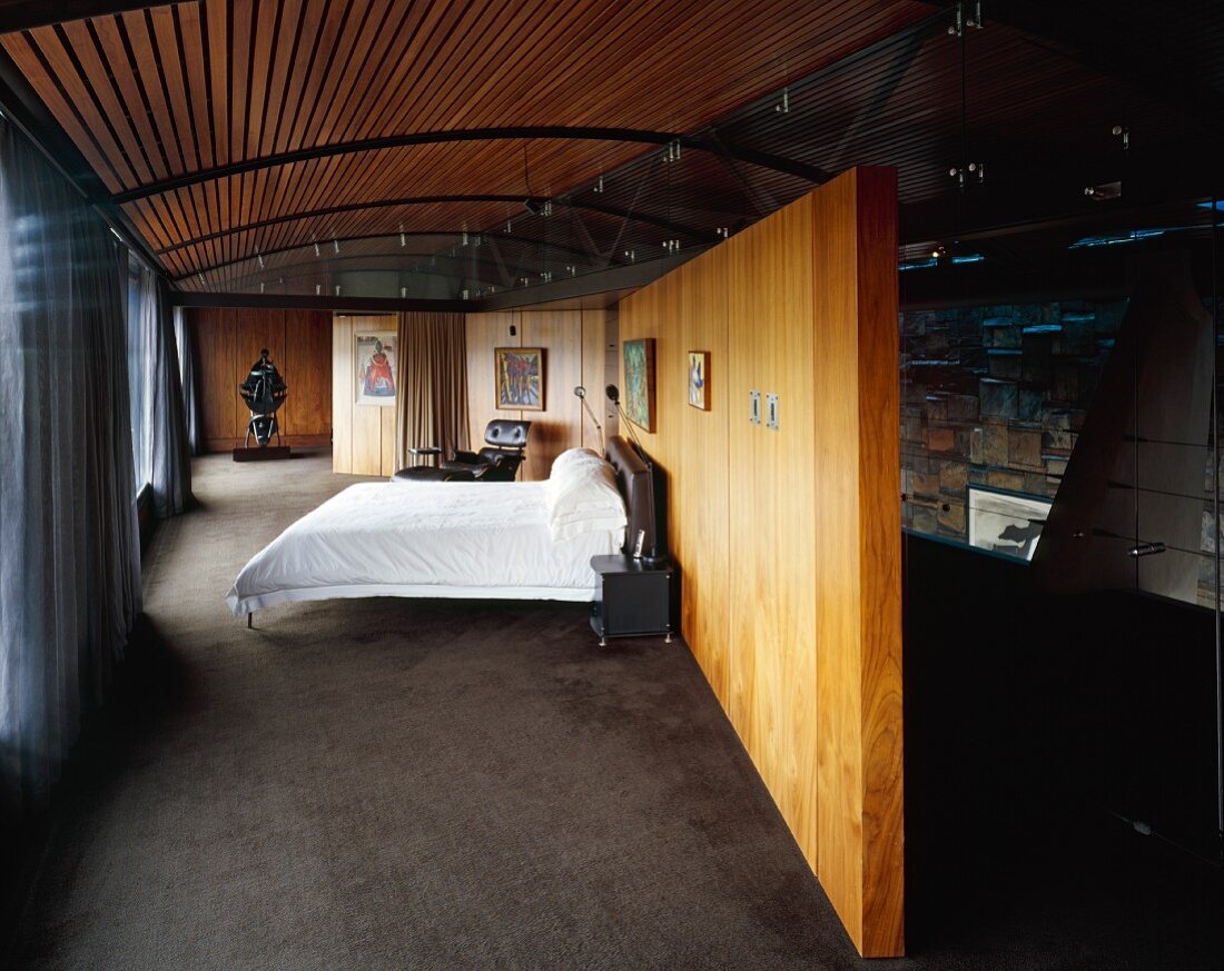 Schlafzimmer mit Doppelbett vor einer Holztrennwand