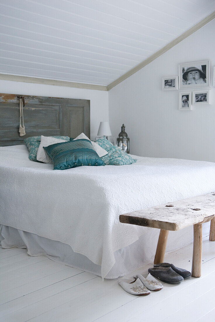 Bright attic bedroom with white bed linen and turquoise-colored pillows
