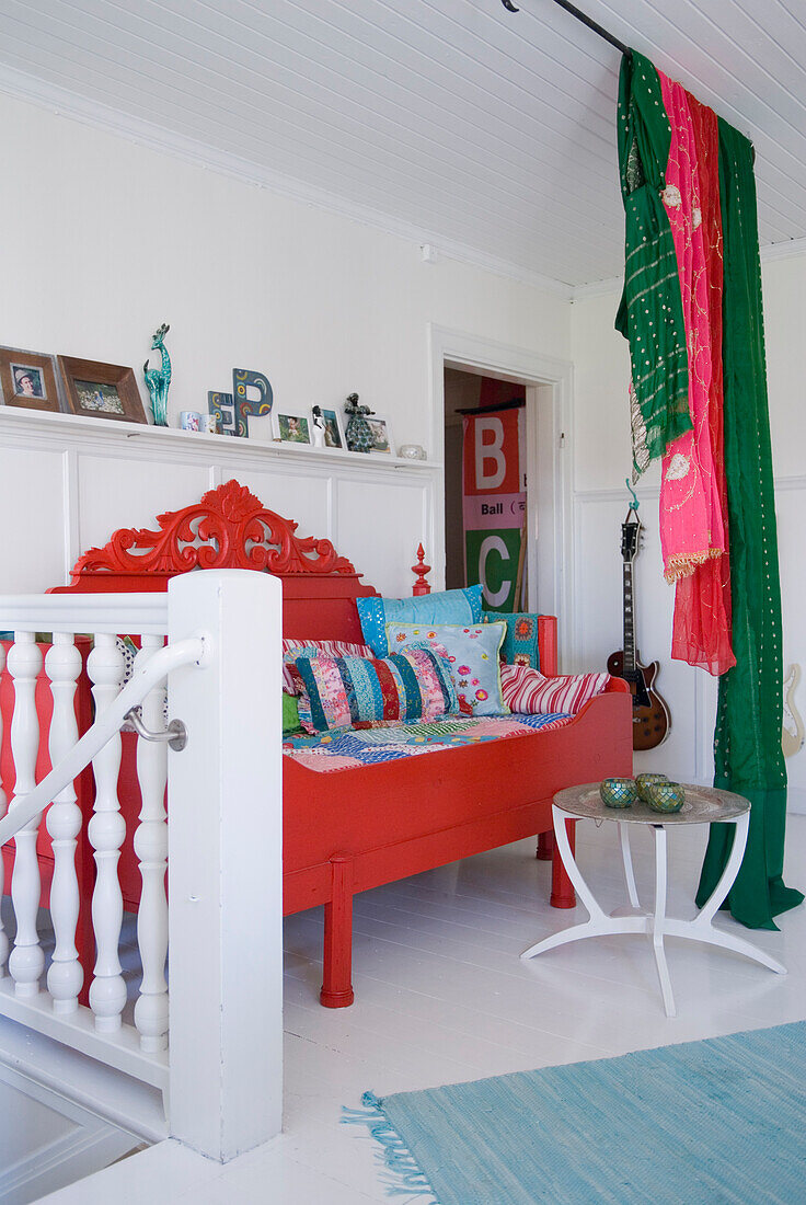 Buntes Wohnambiente mit rotem Tagesbett und grünem Vorhang