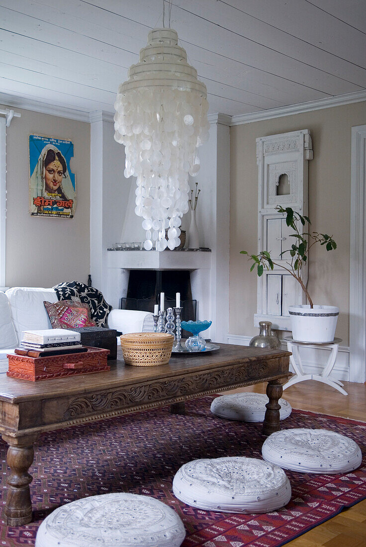 Wohnzimmer mit gemustertem Teppich, weißen Sitzkissen und Kamin
