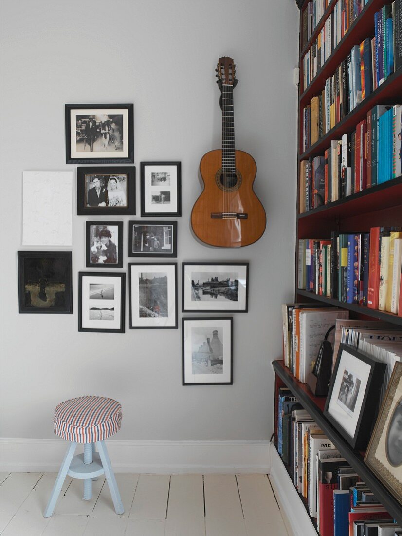 Schwarz-weiße Fotos und eine Gitarre an der Wand neben einem Bücherregal