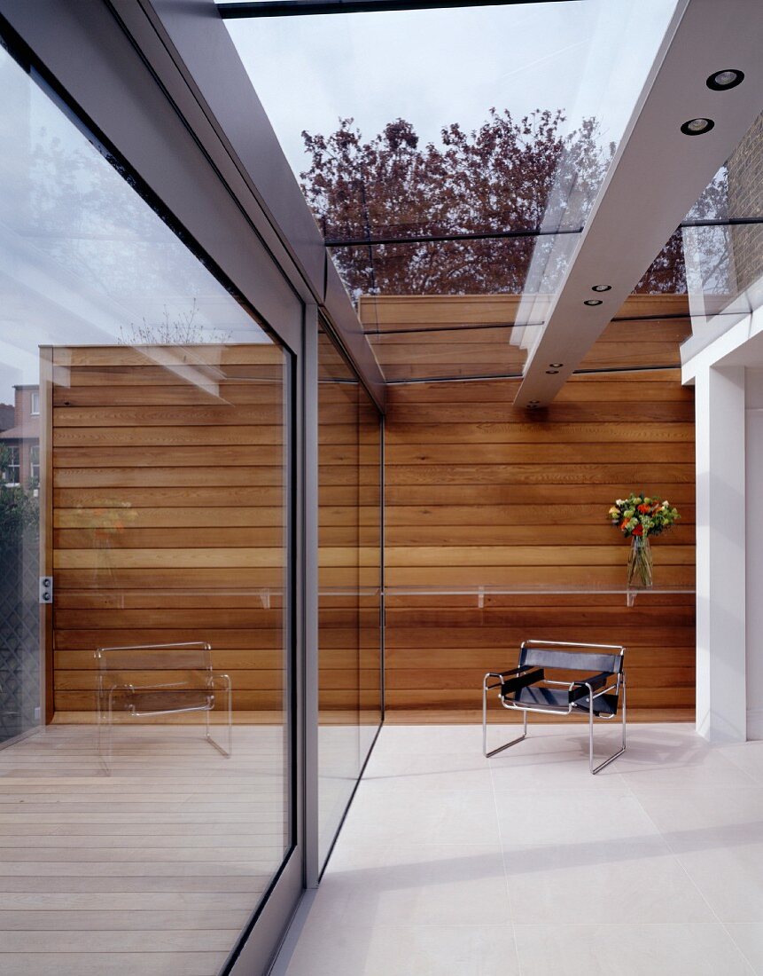 Designer Wohnhaus - Sessel im Bauhausstil in modernem Innenhof mit in Glasdach integrierter Beleuchtung