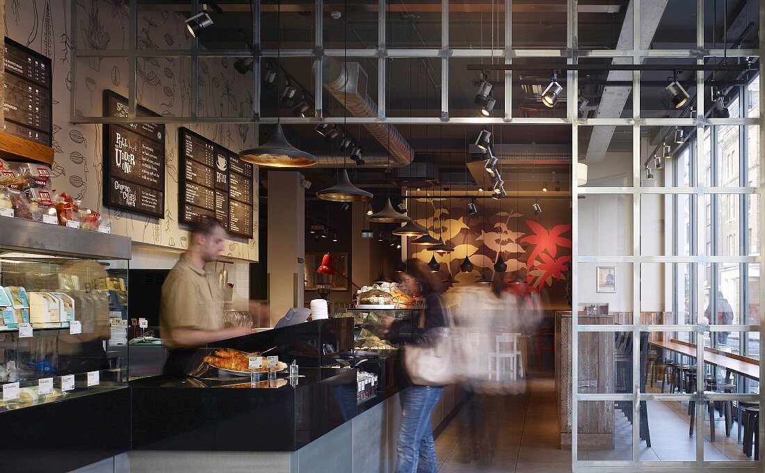 Aufgeglaster Londoner Coffee Shop mit floralem Wandbild und Trennwand aus Metallrahmen