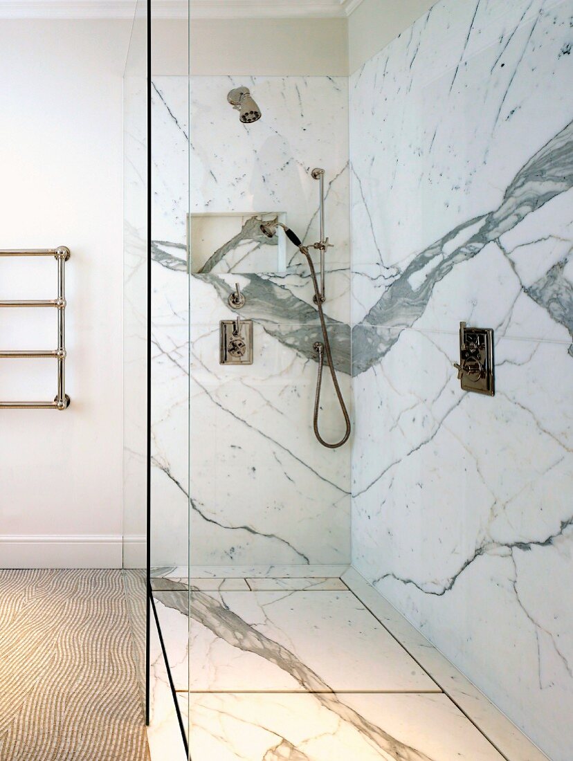 Dramatic marble cladding in floor-level shower with trench drain and glass screen